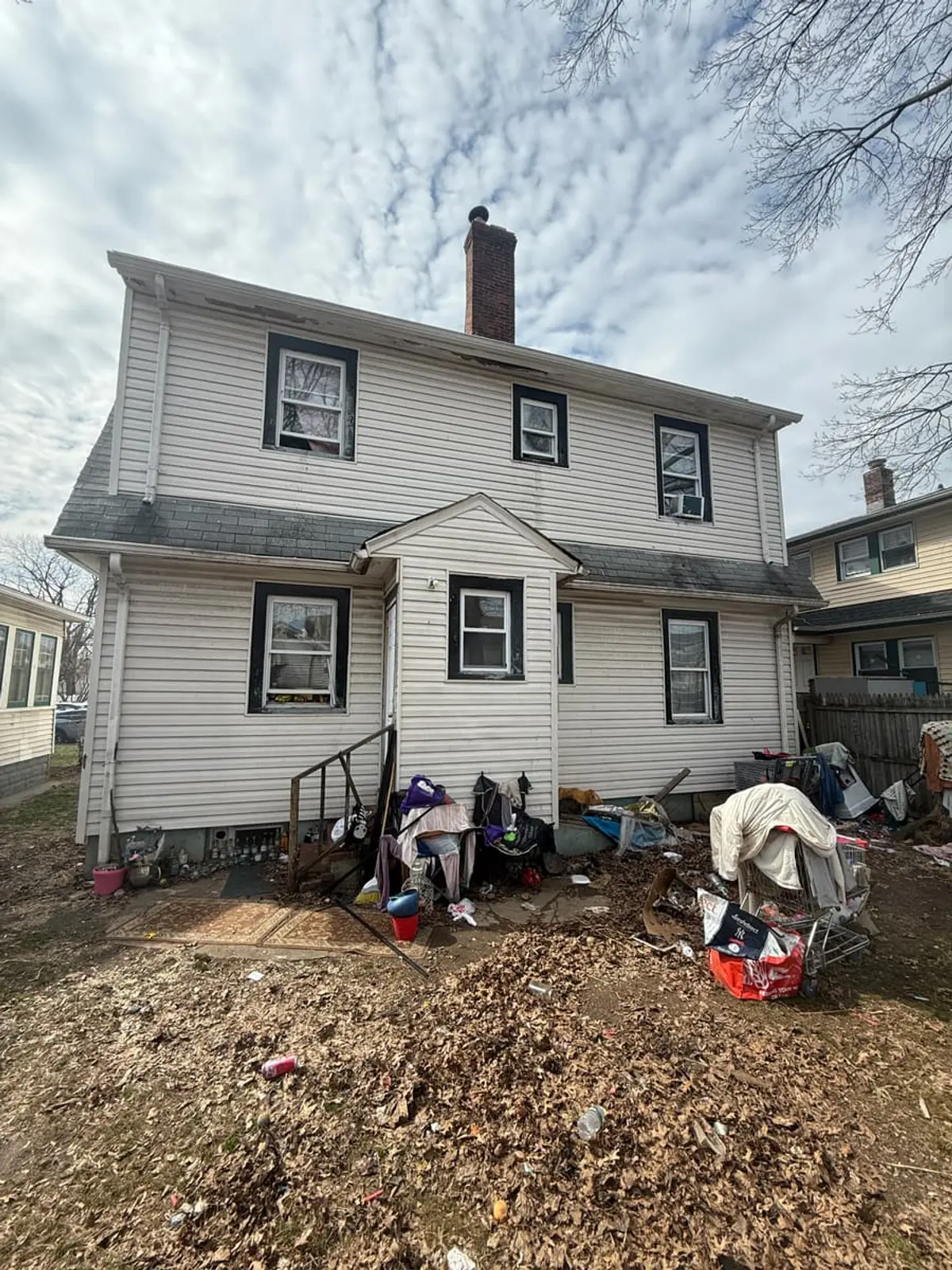 Dealing with squatters or holdover tenants in Hempstead: back of a two-family house with belongings piled in the yard