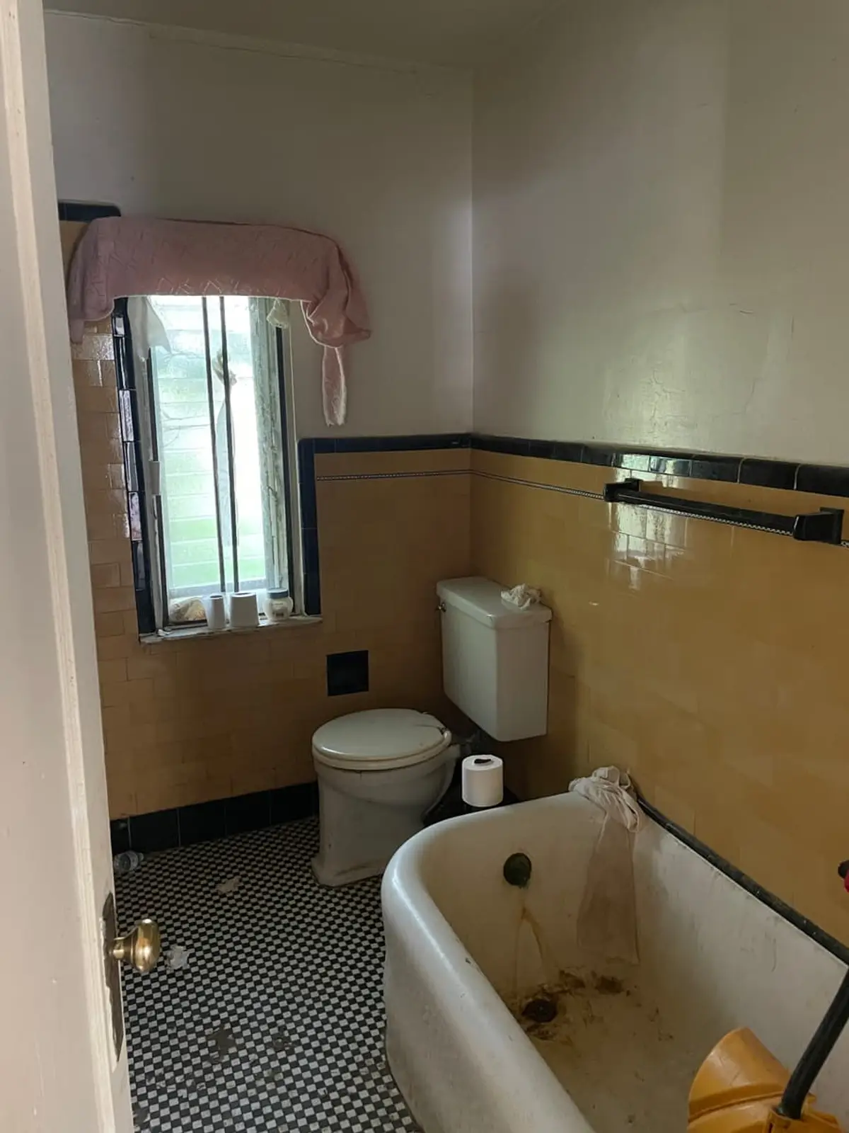 Wondering what your Hempstead house is worth: dated bathroom with yellow tile and a stained clawfoot tub