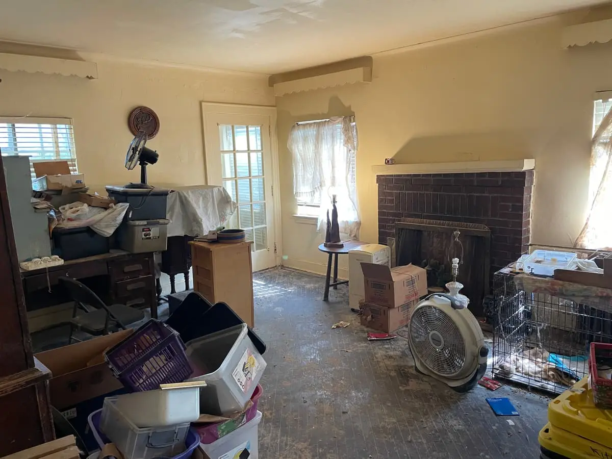 Selling a hoarder house in Hempstead: living room crowded with boxes and bins around a brick fireplace