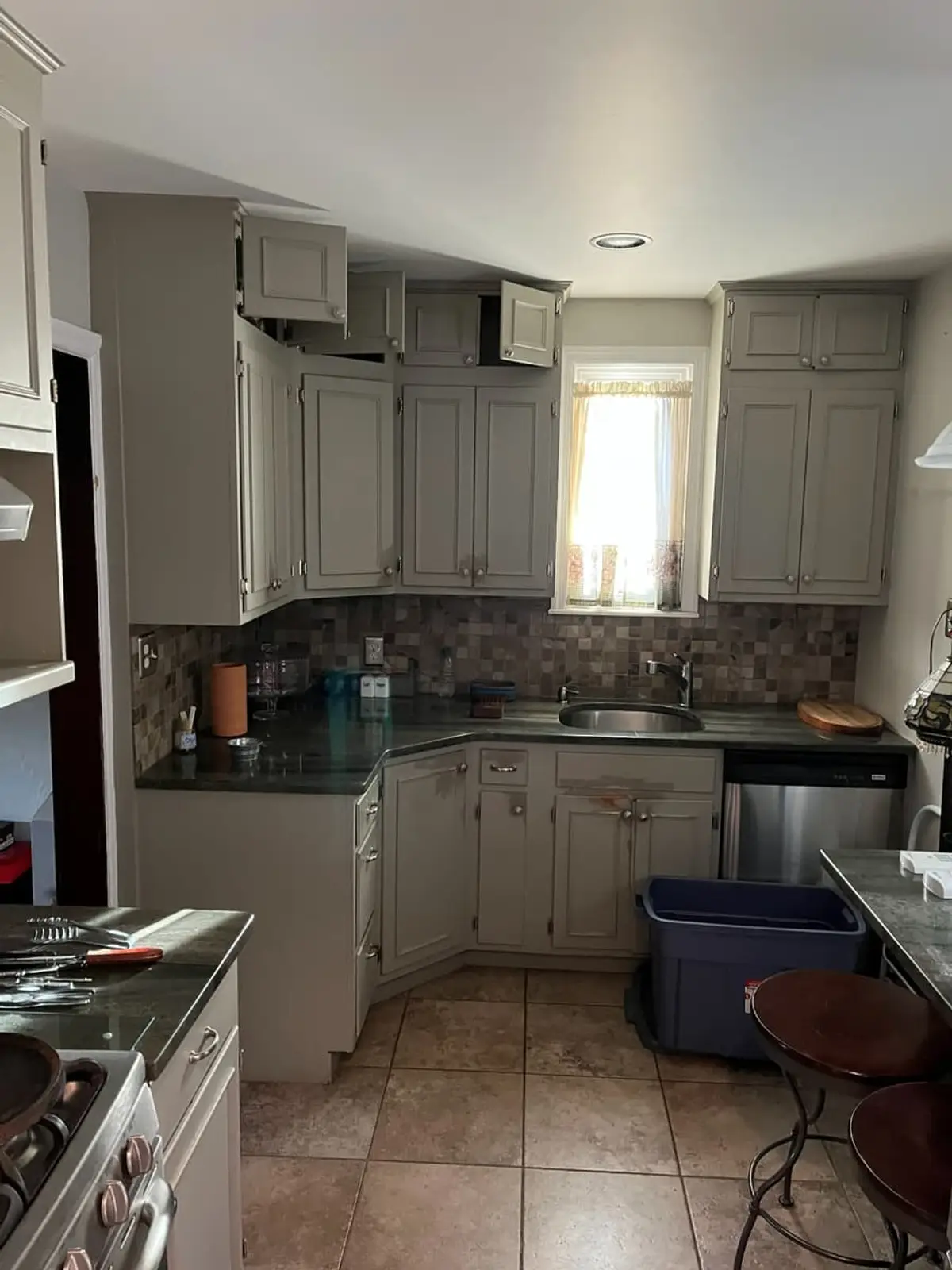 Selling a house with tenants in it in Hempstead: occupied galley kitchen with gray cabinets and a tile floor
