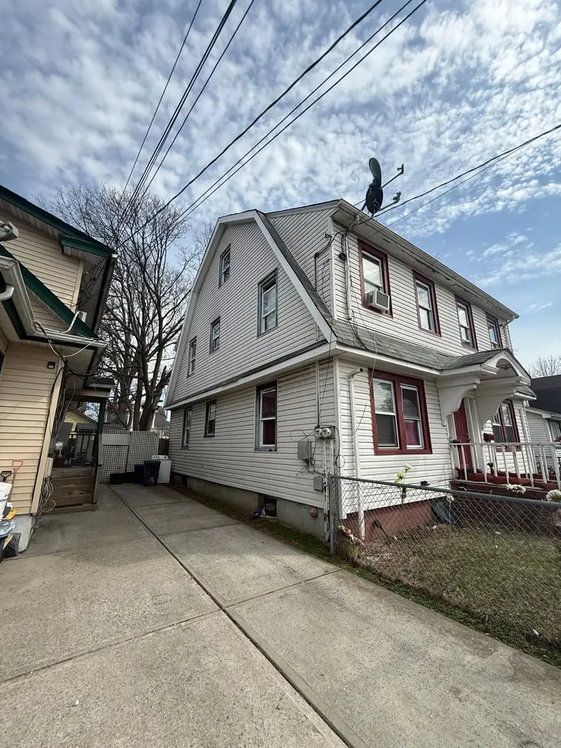 Two-family house with white siding beside a long driveway, Hempstead, NY