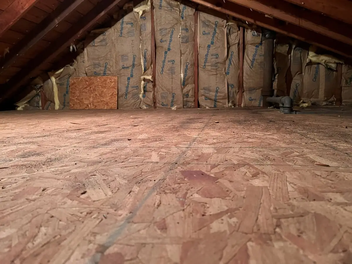 Selling a multi-family house in Hempstead: unfinished attic with a plywood floor and bare rafters