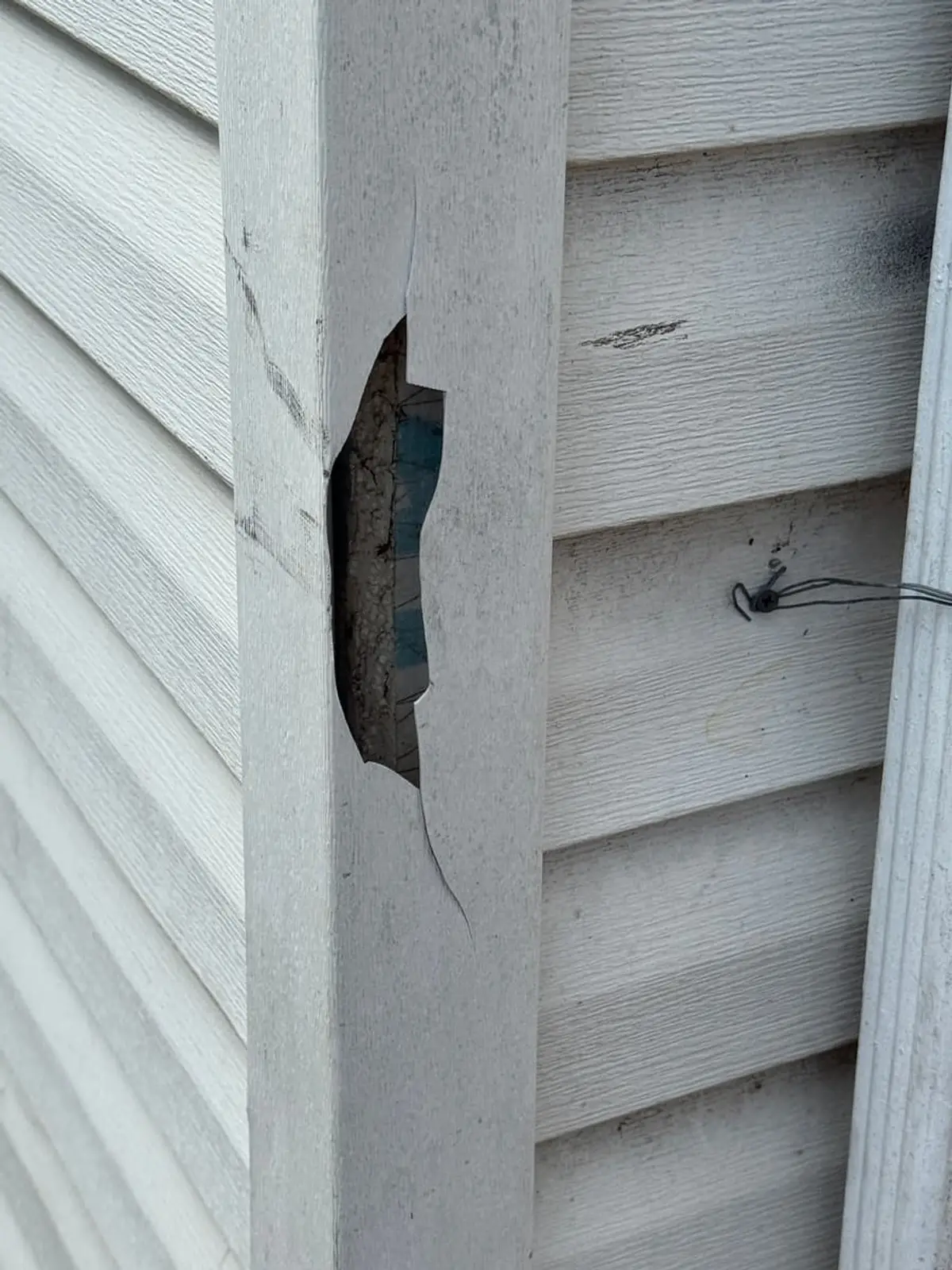 Selling a house with code violations in Hempstead: vinyl siding torn open at the corner of the house